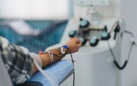 Person undergoing apheresis procedure, donating blood plasma in a hospital setting with medical equipment
