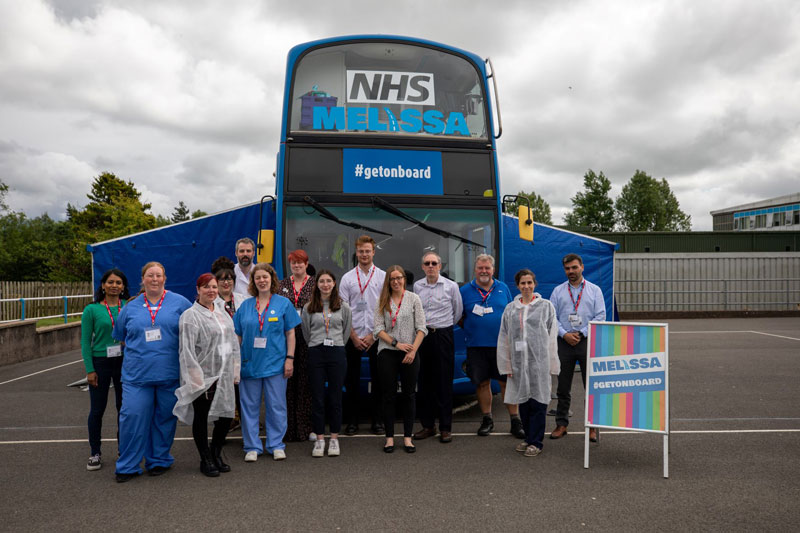 The NHS MELISSA bus team in front of the blue MELISSA bus.