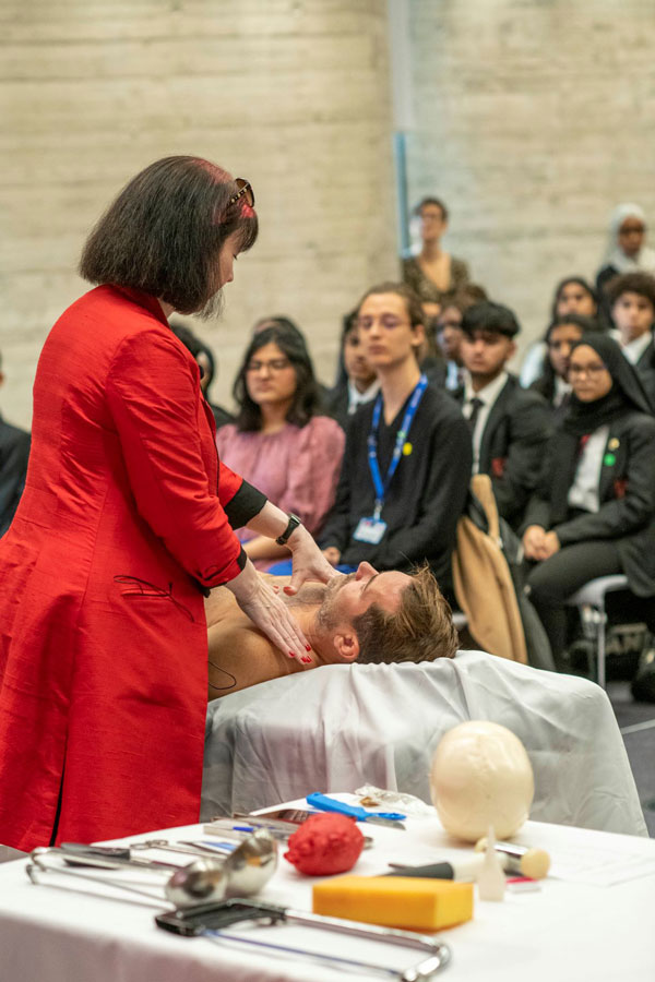 Dr Suzy Lishman standing over an acting dead body with the audience looking on.