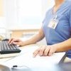 Person in scrubs working at desktop computer