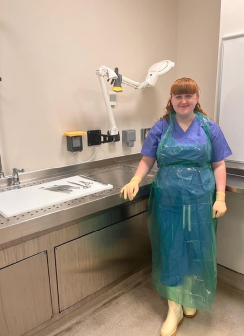 Lucie Williamson smiling to the camera, in a lab with cut up implements on the bench.