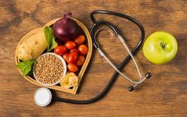 Heart shaped plate of plant-based foods next to a stethoscope and an apple.